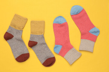 Warm colored socks on a yellow background. Top view