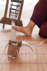 Closeup of foot spinning wooden machine to form thread. Process of making natural cotton wool to fabric. Thai and asian culture. Selective focus.