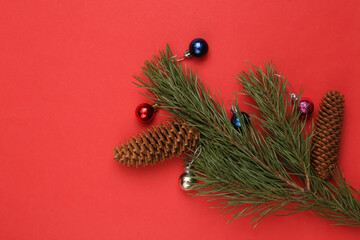 Pine branch with Christmas decorations balls and cones on a red background. Christmas, new year background