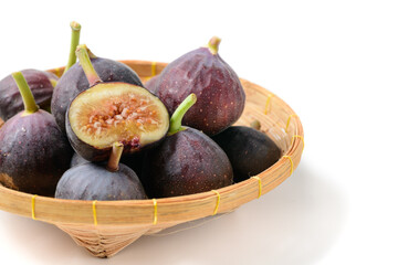 Fresh purple fig fruit and slices in bamboo basket isolated on white background,