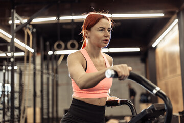 Fototapeta premium Redhead fit woman doing intense cardio training on exercise bike