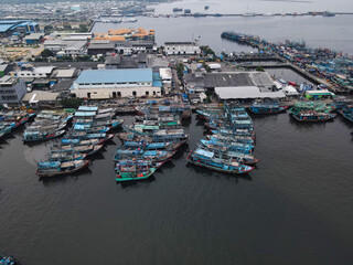 Fototapeta na wymiar Aerial drone view of Muara Angke Beach with wooden boats leaning beside the pier. With noise cloud after rain. Jakarta, Indonesia. March 21, 2021