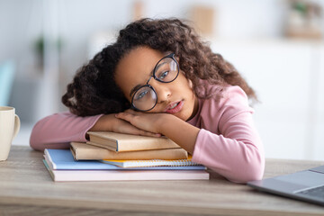 Sleepy african-american teen girl resting head on paper books, tired of school, studying and reading