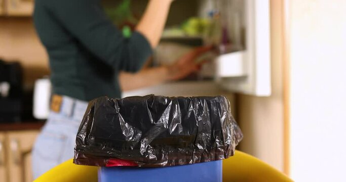 Woman throws in the trash uneaten spoiled products fruits, glasses, from the fridge, wife do daily house cleaning routine, food waste and loss