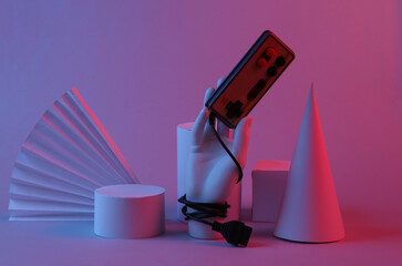 Hand holding retro gamepad, Geometric shapes in red-blue gradient neon light. Gaming concept....