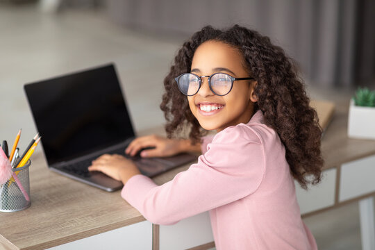 Online Lesson. Over The Shoulder View Of Black Girl Using Laptop With Blank Screen