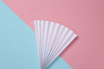 Paper fan on blue-pink pastel background. Concept art, minimalism