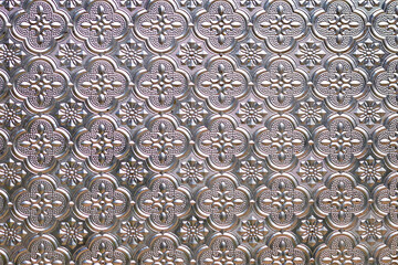 The surface of the glass is exposed to external light. It looks like Thai patterned silverware.