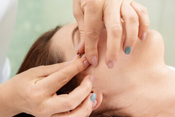 Facial massage close-up. Young, beautiful girl at spa procedures. Skin care, oriental massage treatments, beauty treatments.