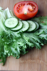 Frieze, tomatoes and cucumber prepared for slicing salad on a wooden background.