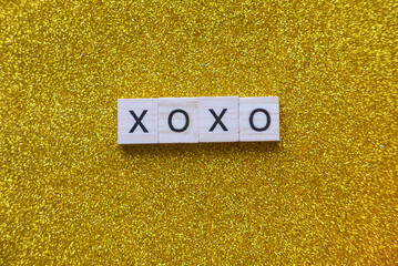 XOXO wooden alphabet on a glitter gold background.
