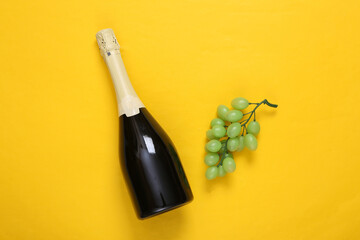 Bottle of wine and grapes on a yellow background