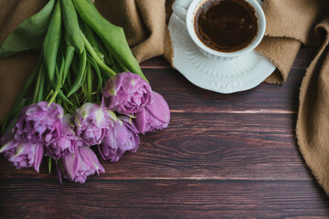 Spring flowers. Bouquet of tulips on a wooden background. Coffee and tulips. Flatley.