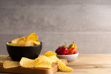 Homemade hot chips with jalapeno peppers on the side . On a dark colored table top.