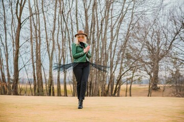 Woman wear eco leather green jacket, Fedora brown hat and vintage aviator glasses , belt with a fringe, trendy concept