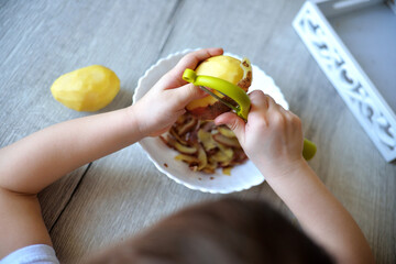Children s hands peeling potatoes with montessori materials for a lesson from the practical life...
