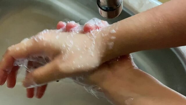 Woman meticulously washing hands with soap as a precautionary to avoid catching covid19 coronavirus