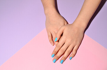 Stylish trendy female manicure. Beautiful young woman's hands on pink and purple background.