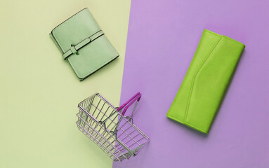 Minimalistic shopping concept. Mini shopping basket and two wallet on pastel background