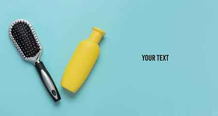 Minimalistic beauty concept. Hair care. Comb and bottle of shampoo on blue background. Top view. Copy space
