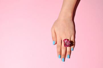 Fototapeta premium Stylish trendy female manicure. Beautiful young woman's hands on pink background with dry roses