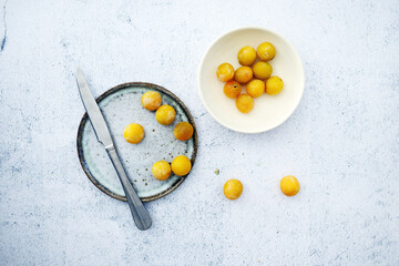 Plum with knife and plate from top view