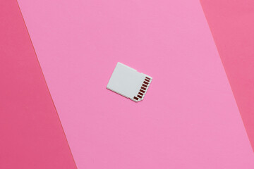 SD memory on pink paper background. Minimalistic technology concept, modern storage media.