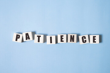 PATIENCE word made with building blocks on blue background