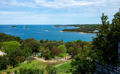 A view from a height towards the sea with many small islands, boats and greenery