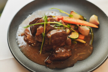 Beef Bourguignon with vegetables in a black plate