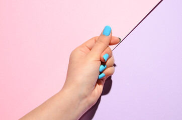 Stylish trendy female manicure. Beautiful young woman's hands on pink and purple background.