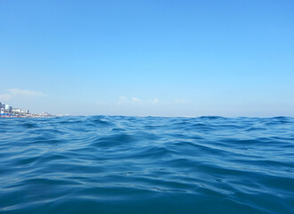 Naklejka na ściany i meble Very blue water near city shore with buildings and deep blue sky