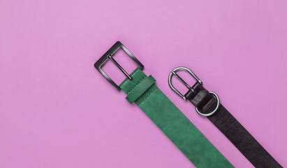 Two leather belts on a pink background close-up