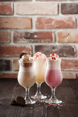 Seto of three milkshakes standing on wooden table