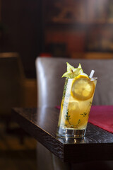 Yellow coctail with carambola on the corner of wooden table