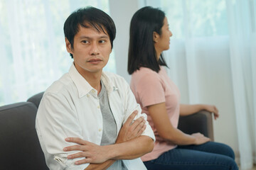 Man sitting back to back to his wife after quarrel at home