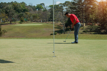 Golfer playing golf in the evening golf course, on sun set evening time. Man playing golf on a golf course in the sun.