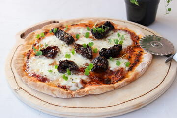 Pizza on a wooden board with mozzarella, mini arugula.
