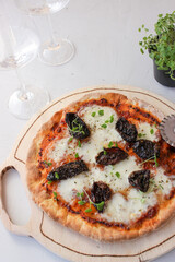 Pizza on a wooden board with mozzarella, mini arugula.