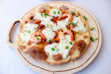 Pizza on a wooden board with mozzarella, mini arugula.