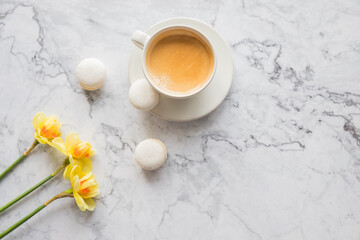 Macaroons with white cup of coffee, bright beautiful flowers on marble background.Beautiful breakfast for woman. Spring concept.Copy space