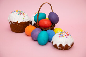 Small basket with beautiful colorful Easter eggs and Easter cakes