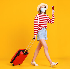 A young masked woman with luggage walking merrily on a yellow background