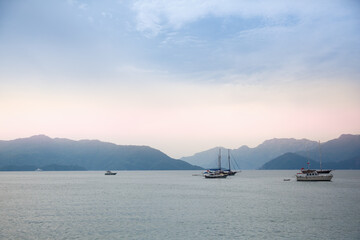 Fisherman boats and yachts in calm sea, blue hills on background, evening dusk, Turkey, Marmaris