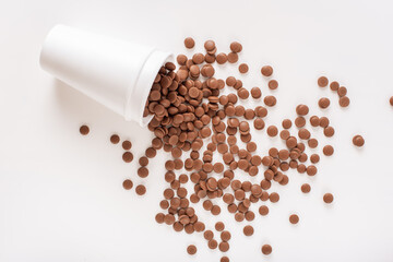 Home confectioner business concept. DIY homemade sweets. Chocolate callets scattered from a disposable cup on a white background. top view close-up. Flat lay.