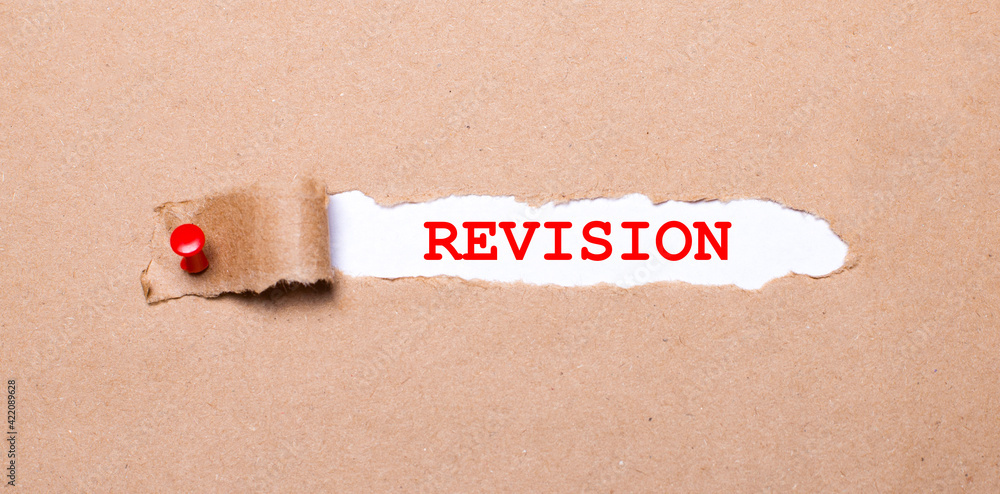 Poster beneath the torn strip of kraft paper attached with a red button is a white paper labeled revision