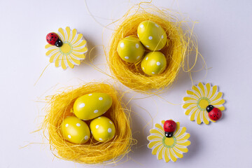Easter eggs in nests and figurines of flowers on a white background.