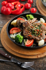 Fried meat with vegetables served on frying pan