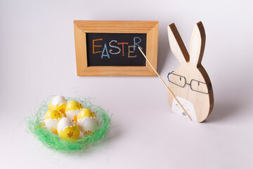 An Easter bunny with a pointer near the board tells the hatched chickens about Easter.