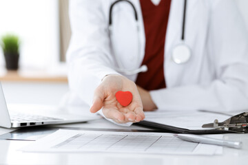 Unknown woman-doctor holding little heart in her hands. Children's cardiology and medical care,...